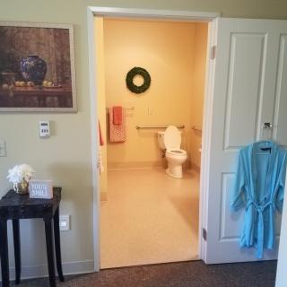 A view of a bathroom through an open doorway, featuring a toilet, towel, and hanging robe.