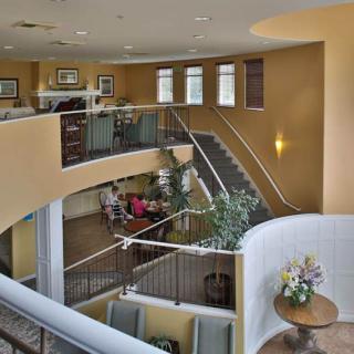 A modern lobby with multiple levels, featuring stairways, seating areas, and decorative plants.