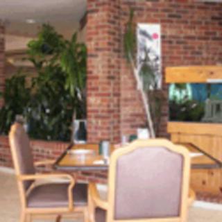 A cozy interior space featuring a table and chairs, with a brick wall, lush plants, and an aquarium.