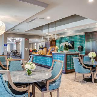 A modern dining area featuring elegant tables and chairs, stylish lighting, and a bar counter with colorful tiles.