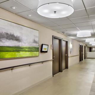 A modern hospital corridor featuring contemporary artwork and bright lighting.