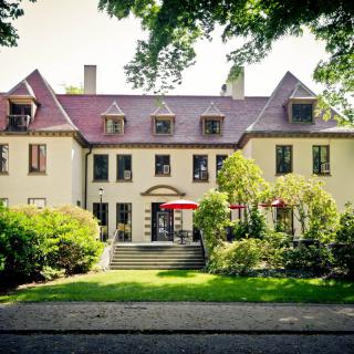 A charming residential house surrounded by lush greenery and trees.