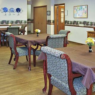 A well-decorated dining room with neatly arranged tables and chairs, adorned with floral centerpieces.