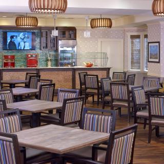 Empty restaurant dining area with neatly arranged tables, chairs, and warm lighting.