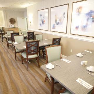 A well-lit dining area featuring neatly arranged tables and chairs, adorned with abstract artwork on the walls.