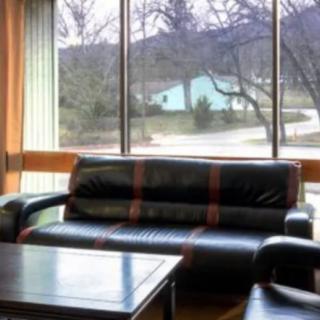 A cozy living room with a black sofa and coffee table, overlooking a scenic outdoor view.
