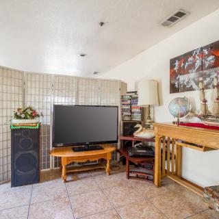 A cozy living room with a television, various furniture pieces, and decorative items.