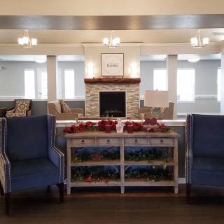 A cozy living room featuring a fireplace, two armchairs, and decorative elements.
