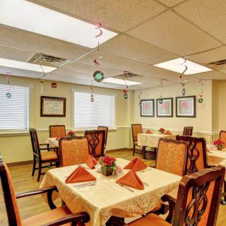 A cozy dining room with tables set for guests, featuring warm lighting and elegant decor.