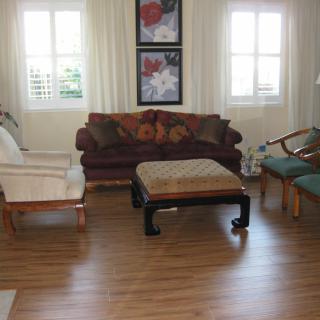 A cozy living room with a sofa, armchairs, and a central coffee table on wooden flooring.