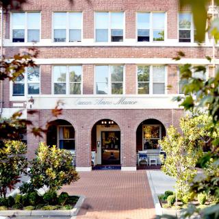 A charming brick building entrance surrounded by trees and greenery.