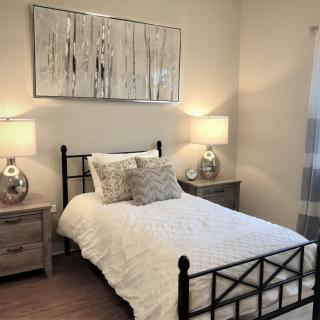 A cozy bedroom with a neatly made bed, bedside tables, and decorative lamps.