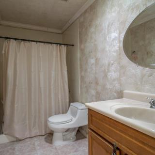 A clean and simple bathroom with a toilet, sink, and shower area.