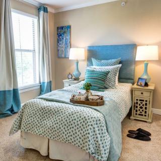 A cozy bedroom with a single bed, decorative pillows, and matching curtains.