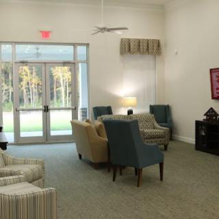 A cozy living room with comfortable seating, soft lighting, and large windows overlooking greenery.