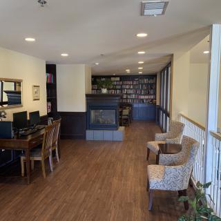 A cozy library corner with bookshelves, a fireplace, and computer workstations.