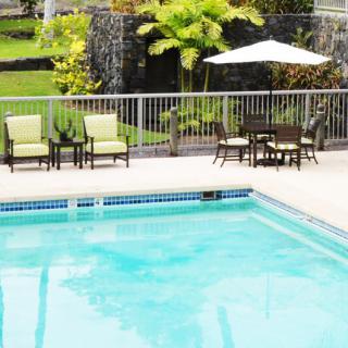 A serene outdoor swimming pool area with patio furniture and tropical landscaping.