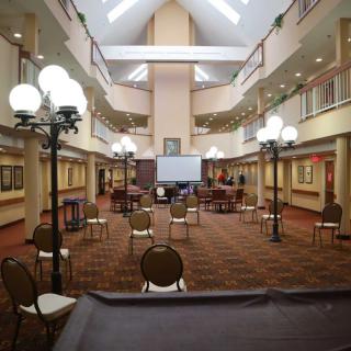 An indoor conference room setup with chairs organized around a central projector screen and surrounded by decorative lamps.
