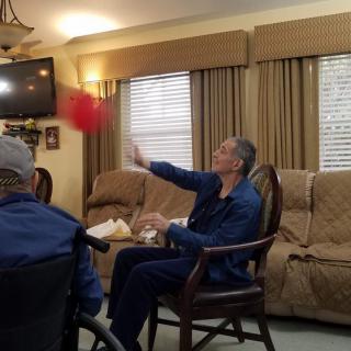 Residents in a care home engaging in a ball game as part of their indoor activities.