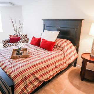 A cozy and stylish bedroom featuring a striped bedspread, accent pillows, and modern decor.