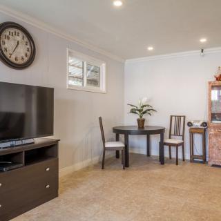 A cozy living room with a television, clock, and a small dining area.