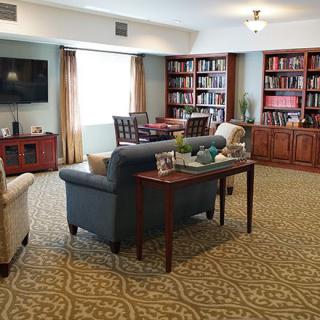 A cozy living room featuring sofas, bookshelves, a television, and a decorative carpet.