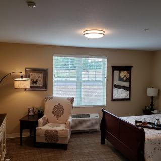 A cozy bedroom with a wooden bed, comfortable chair, and decorative artwork on the walls.