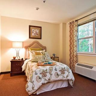 A cozy bedroom with a neatly made bed, soft lighting, and warm decor.