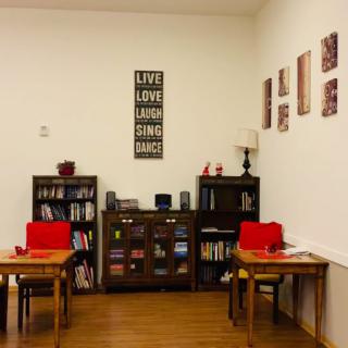 A cozy reading corner with bookshelves, tables, and a lamp.