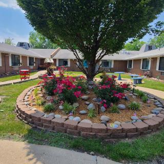 A beautifully landscaped courtyard featuring vibrant flowers and a large tree, providing a peaceful outdoor environment.