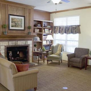 A cozy living room with a fireplace, sofa, armchairs, and a bookshelf.