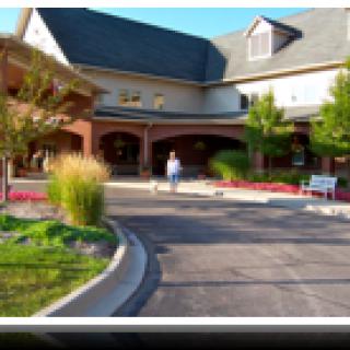 A person walking towards a large building entrance surrounded by landscaped greenery.