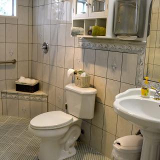 Modern bathroom with tiled walls, a toilet, and a pedestal sink.