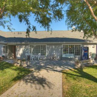 A charming house with a front yard featuring a pathway and trees, illuminated by sunlight.