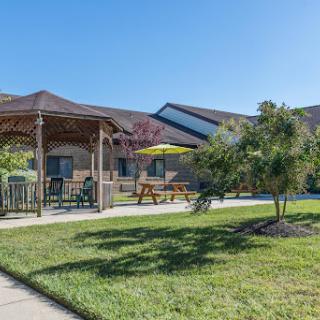 A sunny outdoor seating area featuring a gazebo and well-maintained grass.
