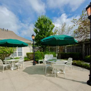 A sunny outdoor patio with tables and chairs under green umbrellas.