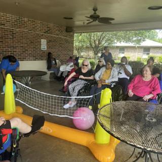 Seniors enjoying a social gathering outdoors, engaged in activities with friends.