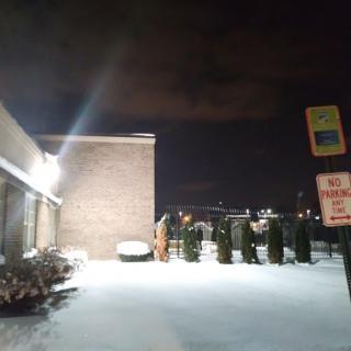 A snowy night scene featuring a building illuminated by outdoor lights.