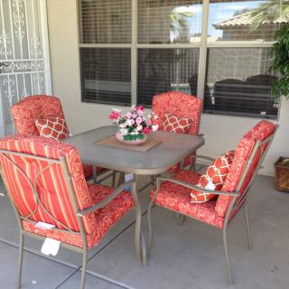 A cozy outdoor patio setup with a table and four cushioned chairs.