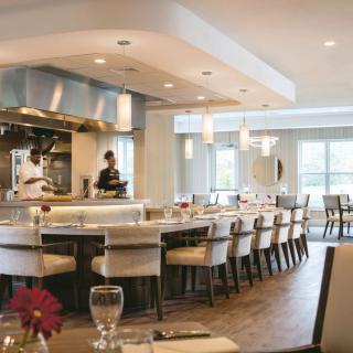 A modern restaurant interior featuring an open kitchen and elegant dining area.