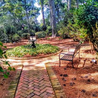 A serene garden pathway surrounded by lush greenery and inviting benches.