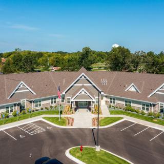 Aerial view of a suburban building with a parking lot and surrounding trees.