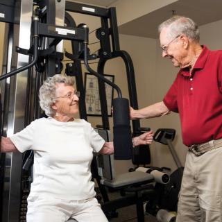 Two seniors enjoying a workout session on strength training equipment.