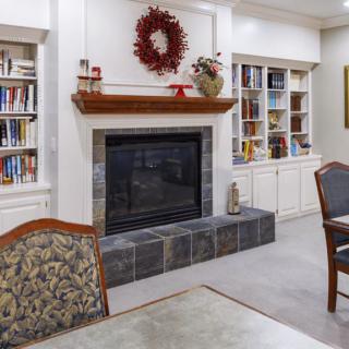 A cozy living room featuring a fireplace surrounded by built-in bookshelves and decorated with a wreath.