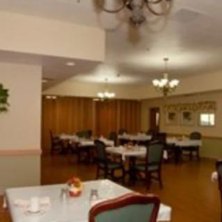 An elegantly set dining room with multiple tables and chairs, featuring chandeliers for lighting.