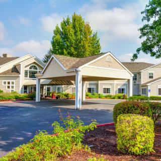 A residential building with a driveway and landscaped entrance.