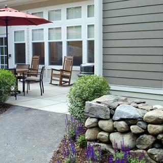 A cozy outdoor patio with a dining set, umbrella, and well-maintained garden.