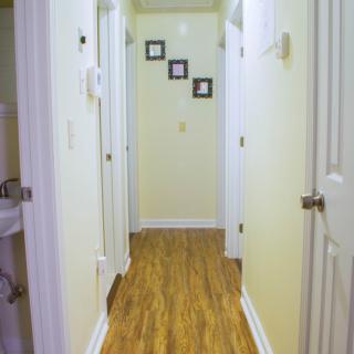 A hallway with wooden flooring and decorated walls featuring framed pictures.