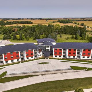 Aerial view of a modern residential building with red accents surrounded by greenery.