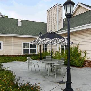 A cozy outdoor patio area with a table, chairs, and an umbrella next to a building.